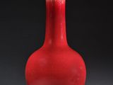 red vase on a gray surface with a black background