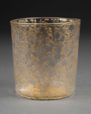 un vieux verre décoré de peinture dorée, posé sur une table