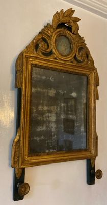 un miroir accroché au mur, sur lequel se trouve une horloge