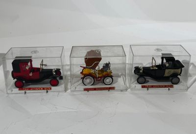 trois petites voitures miniatures dans une boîte transparente posée sur une surface blanche