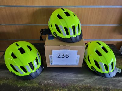 trois casques posés sur une boîte en carton devant un mur en bois