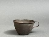 an old cup sitting on top of a table next to a white wall