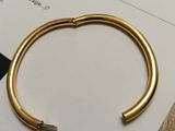 the gold bracelet is laying on top of a piece of paper