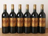 six bottles of red wine lined up on a wooden table