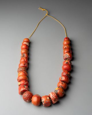 un gros plan d'un collier composé de perles orange sur un fond gris
