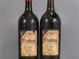 two bottles of red wine sitting on top of a glass table