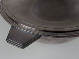 a large metal bowl with a lid on a white table