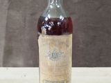 an old bottle of wine sitting on a table with a brown wall in the background