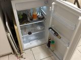 a small refrigerator that is open in the kitchen