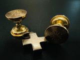 deux boutons métalliques dorés et une croix sur un fond noir