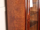 a wooden cabinet with a glass door in the corner of a room