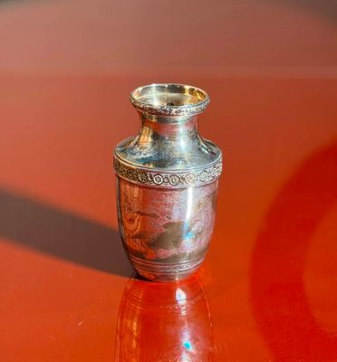 a small silver vase sitting on a red table