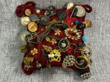 un gros plan sur un coussin rouge sur lequel sont disposés plusieurs bijoux