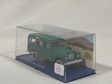 a green toy car in a clear box on a white surface