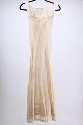 a white dress hanging on a hanger against a white wall