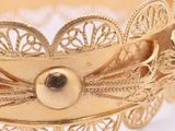 a close up of a gold bracelet on a white surface