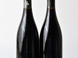 two bottles of wine sitting on top of a wooden table next to each other