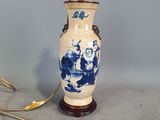 un vase bleu et blanc posé sur une table sur laquelle se trouve une lampe
