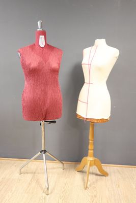 deux mannequins assis sur un socle devant un mur gris