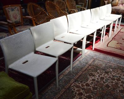 Plusieurs chaises blanches sont alignées en rangée dans une pièce