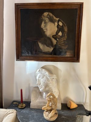 a painting on the wall above a table with a statue of a woman