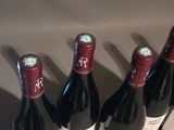 four bottles of wine are lined up on a shelf