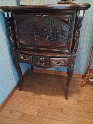 une armoire en bois ornée de sculptures, placée à côté d'un fauteuil à bascule