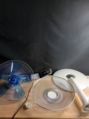 un ventilateur posé sur une table en bois, à côté d'un autre ventilateur