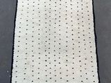 a close up of a white rug with black dots on it