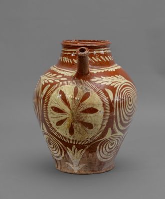 a brown vase with designs on it on a gray surface