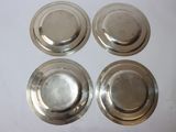 four silver plates are sitting on a white surface