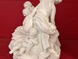 white porcelain sculpture of a woman and child on a rock