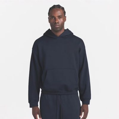 a man in a black hoodie and sweatpants stands in front of a white background