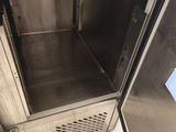 une armoire en acier inoxydable dont la porte est ouverte, dans une cuisine