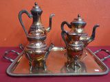 two silver teapots sitting on a tray on a table