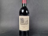 a bottle of wine sitting on top of a table next to a gray background
