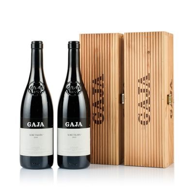 deux bouteilles de vin posées devant une caisse en bois sur une surface blanche