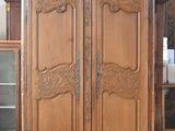 une grande armoire en bois dans une pièce où se trouve une horloge accrochée au mur