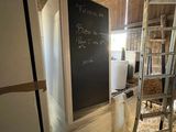 un réfrigérateur dans une grange, avec un tableau noir sur la porte
