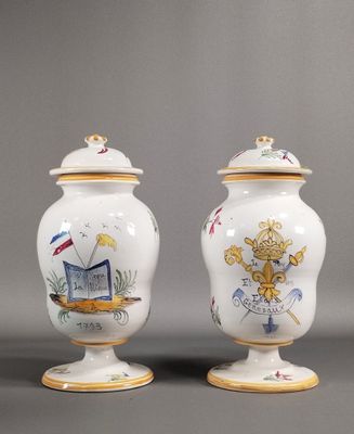 deux vases blancs ornés de motifs dorés et bleus sur un fond gris