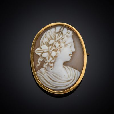 un gros plan sur une broche blanche et dorée représentant le visage d'une femme
