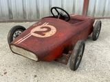 a red pedal car with a dollar symbol painted on it