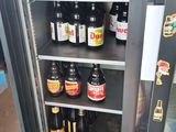 a person standing in front of a refrigerator filled with beer