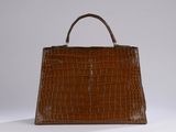 a brown crocodile skin handbag on a white surface