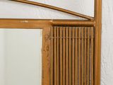 a mirror hanging on the wall with a bamboo frame