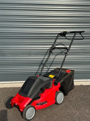 une photo d'une tondeuse à gazon rouge garée devant la porte d'un garage