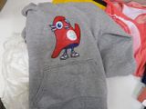 grey hoodie with a cartoon character on it sitting on top of a pile of clothes