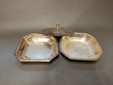 two silver plated dishes with lids on a table
