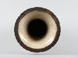 a brown vase with a black rim sitting on a white surface