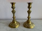 two gold candlesticks sitting on a marble table